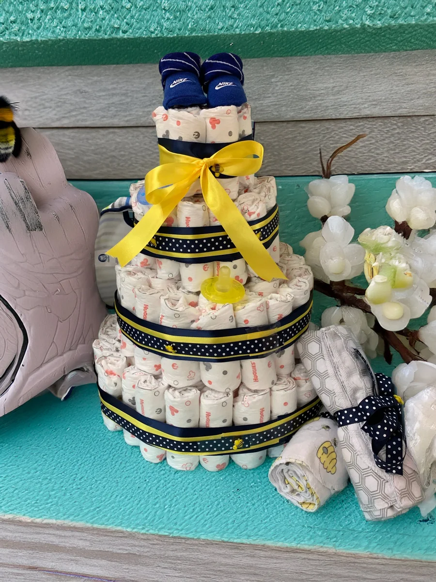 Baby shower diaper cake with yellow ribbon and navy accents on a teal table