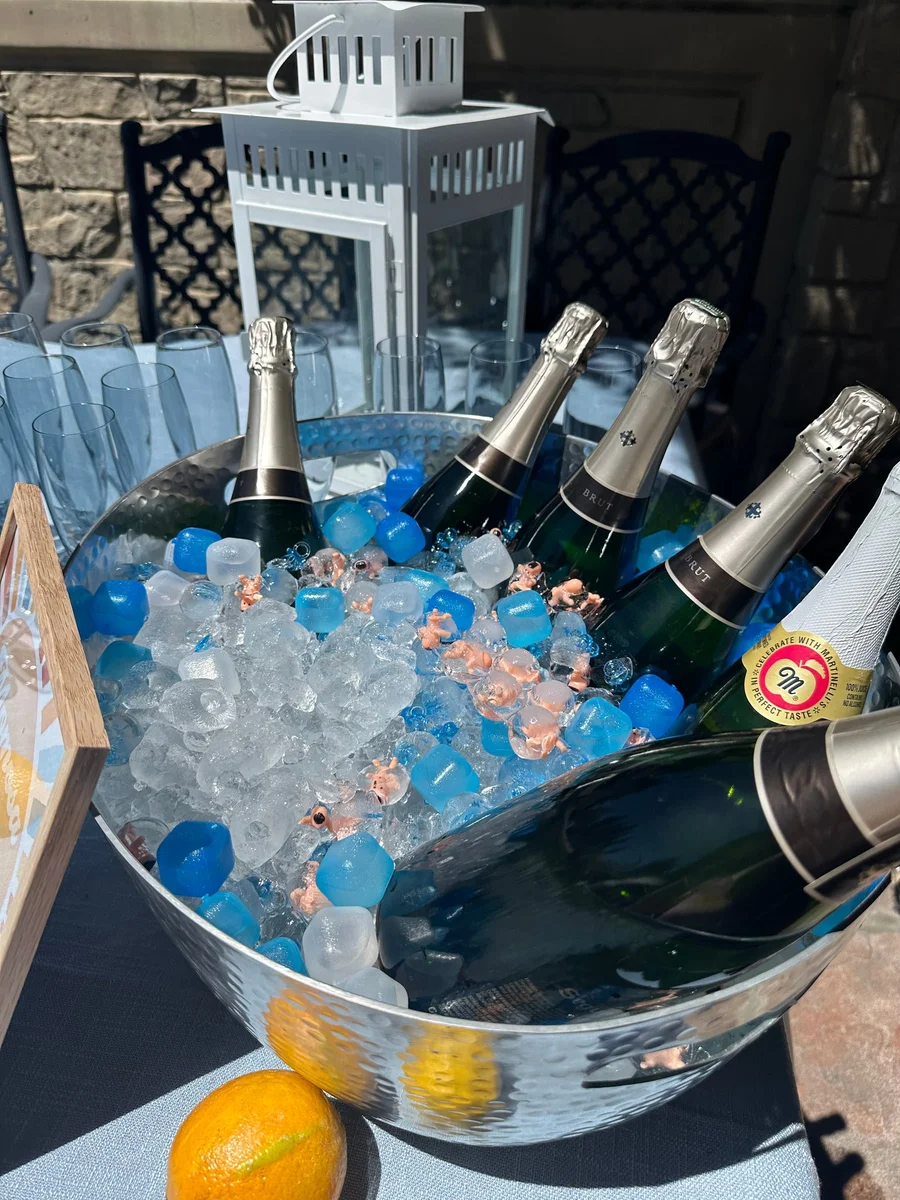 Champagne bottles chilling in an ice bucket with lemons on a pale blue table