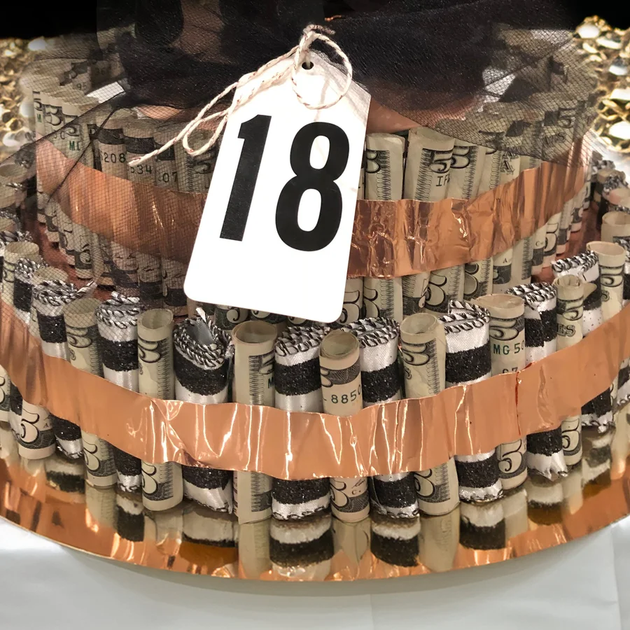 Money cake of rolled bills wrapped in copper ribbon with a number 18 tag