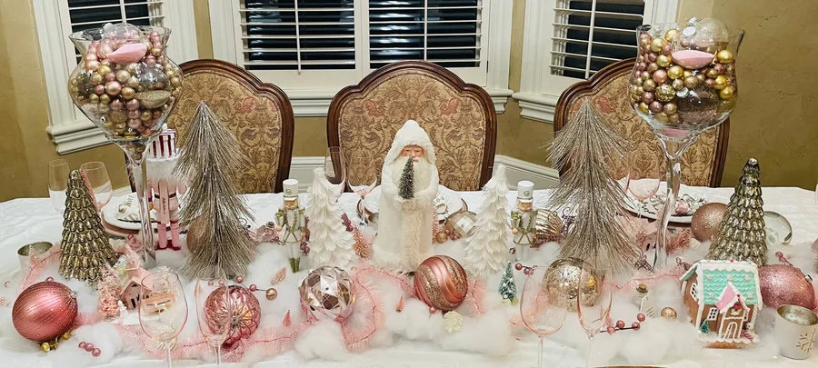Pink and white holiday tablescape with miniature trees and ornaments on a long table