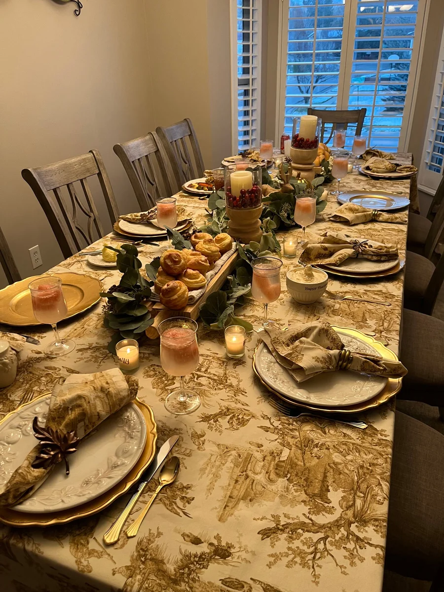 Formal dining table set with gold linens, candles and napkins for a family dinner