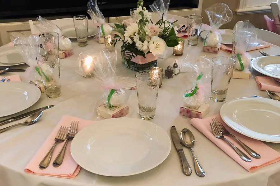 Elegant round table set with pink napkins, flatware and floral centerpieces