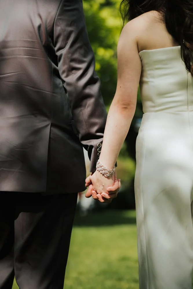 Close-up of a couple holding hands, the woman in a strapless white dress