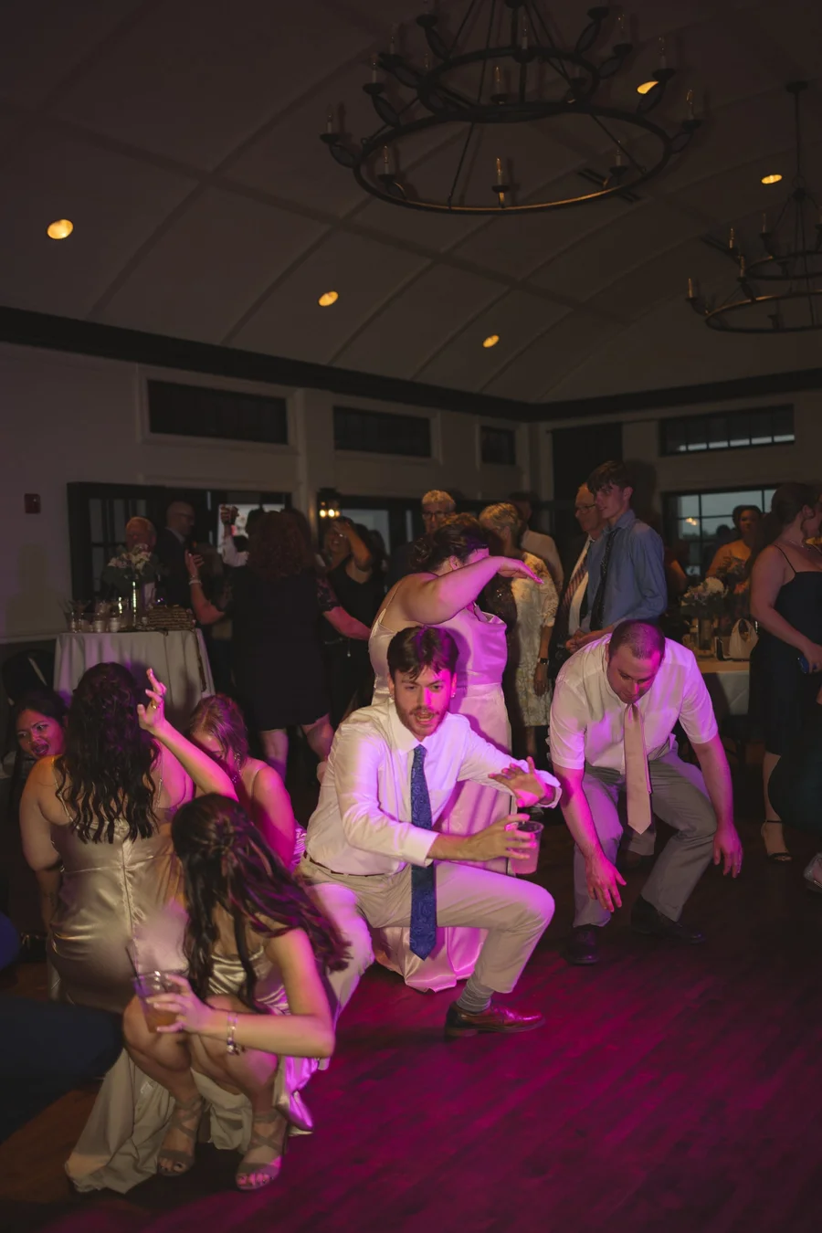 Guests crouching and dancing on a dim dance floor with purple lighting