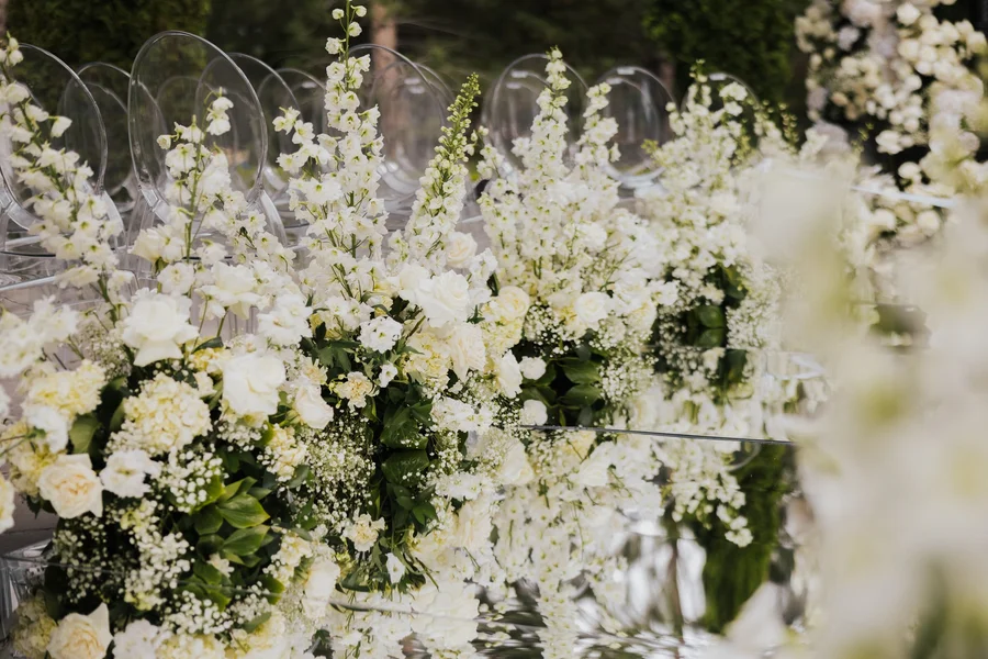 Lush white and green floral arrangement lining the ceremony aisle