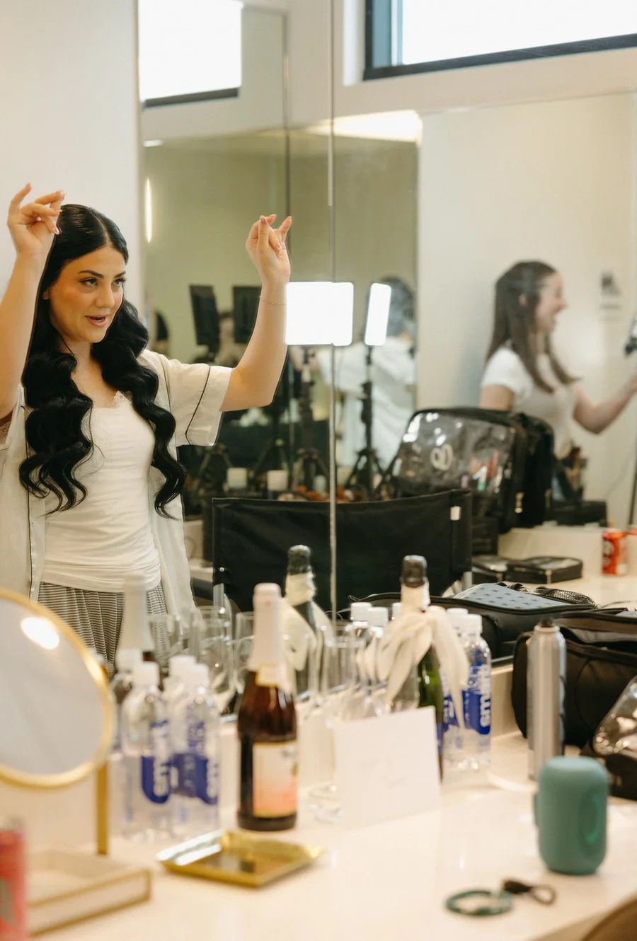 Woman raising her arms by a makeup station in a bridal preparation room