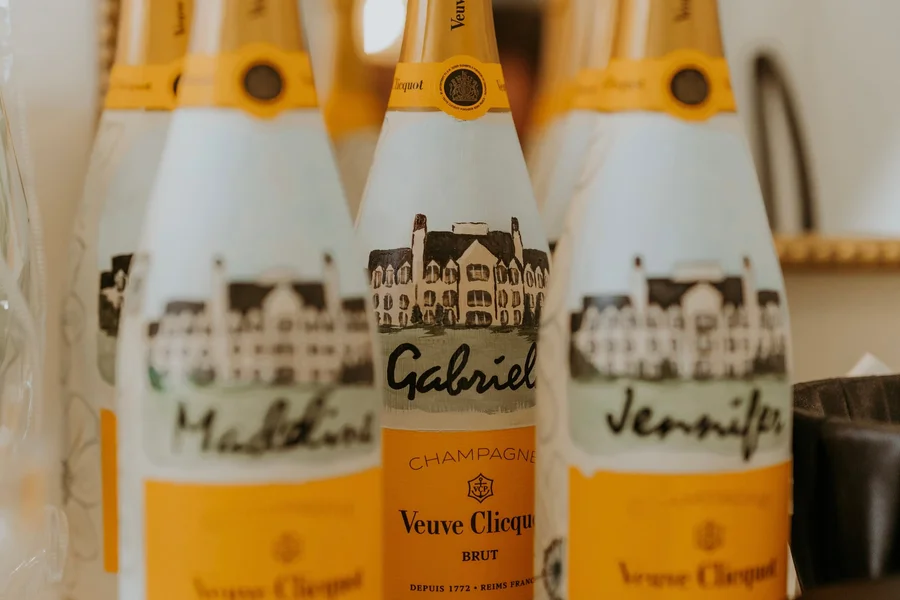 Champagne bottles labeled with individual guest names on a table